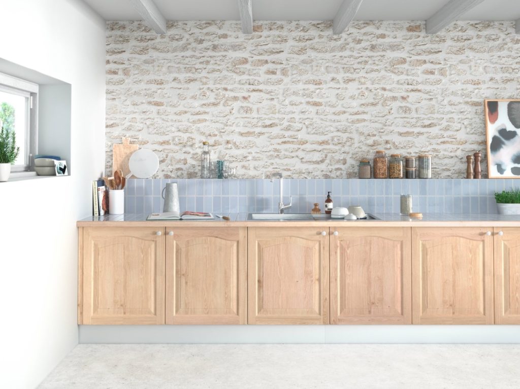 Meuble de cuisine en bois clair dans un intérieur clair avec un mur en brique