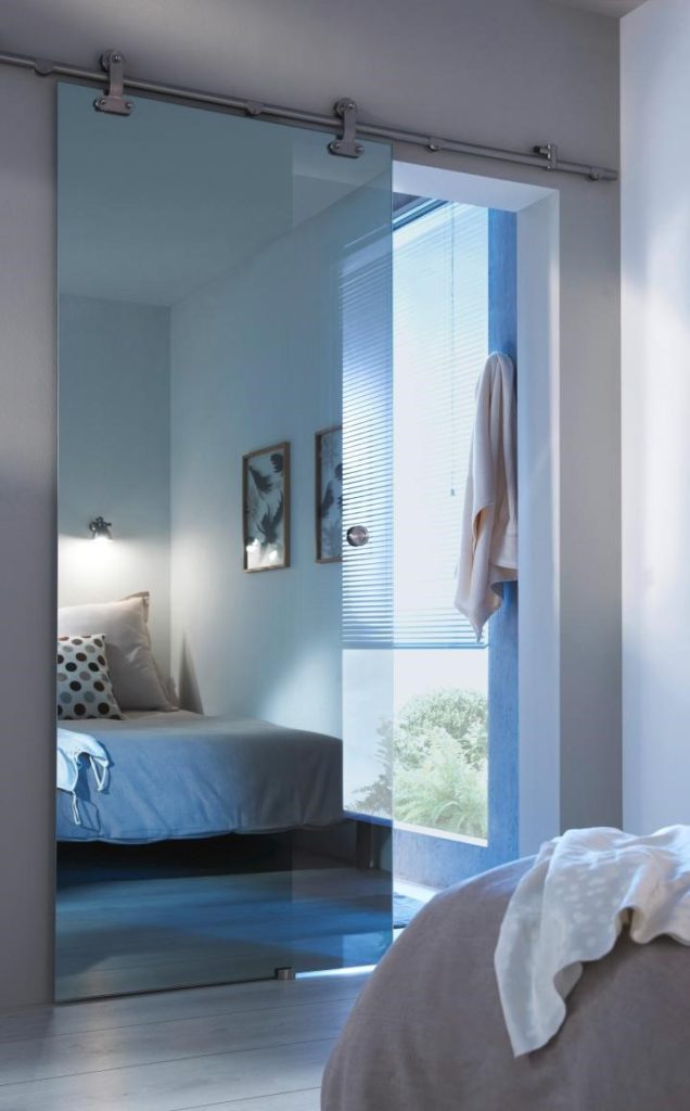 Porte coulissante effet miroir dans une chambre aux tons gris bleu