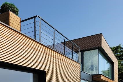 Terrasse en hauteur d'une maison aux tons bois, avec balustrade noire