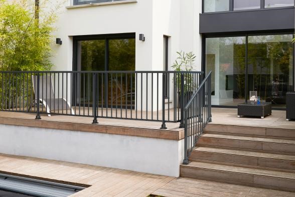 Grande terrasse avec balustrade noire et plancher en bois