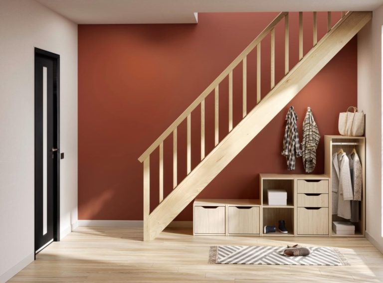 Rangement sous escalier en bois devant mur rouge orangé