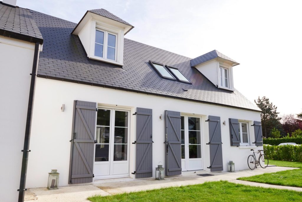 extérieur d'une maison blanche avec toit et volets noirs