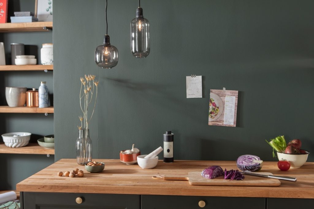 Plan de travail en bois contre mur gris foncé, luminaire et décoration