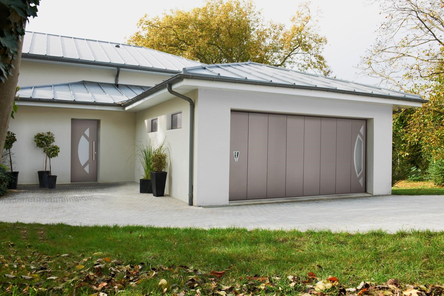 Porte de garage coulissante latérale d'une grande maison entourée de verdure