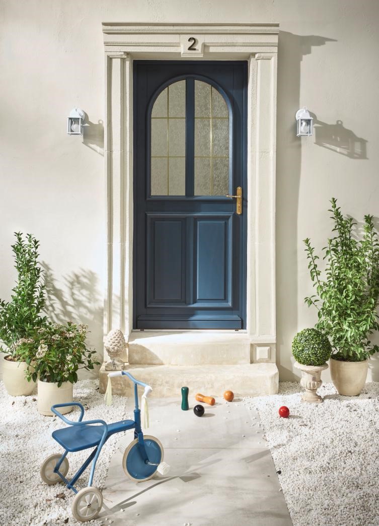 Porte d'entrée en bois bleue entourée de plantes et de jouets d'enfants