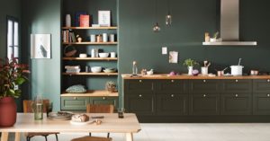 Cuisine aux tons vert foncé et bois avec table à manger et objets décoratifs