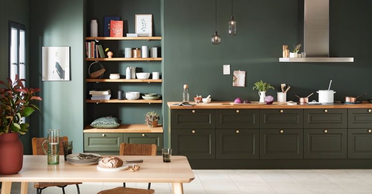 Cuisine aux tons vert foncé et bois avec table à manger et objets décoratifs