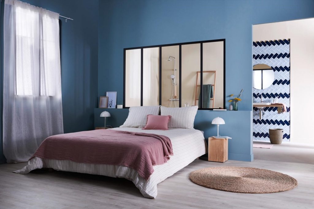 Verrière vitrée séparant une chambre aux tons bleuet de sa salle de bain