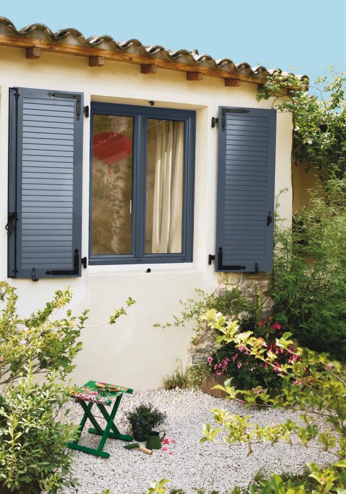 maison jaune avec volets en aluminium gris foncé