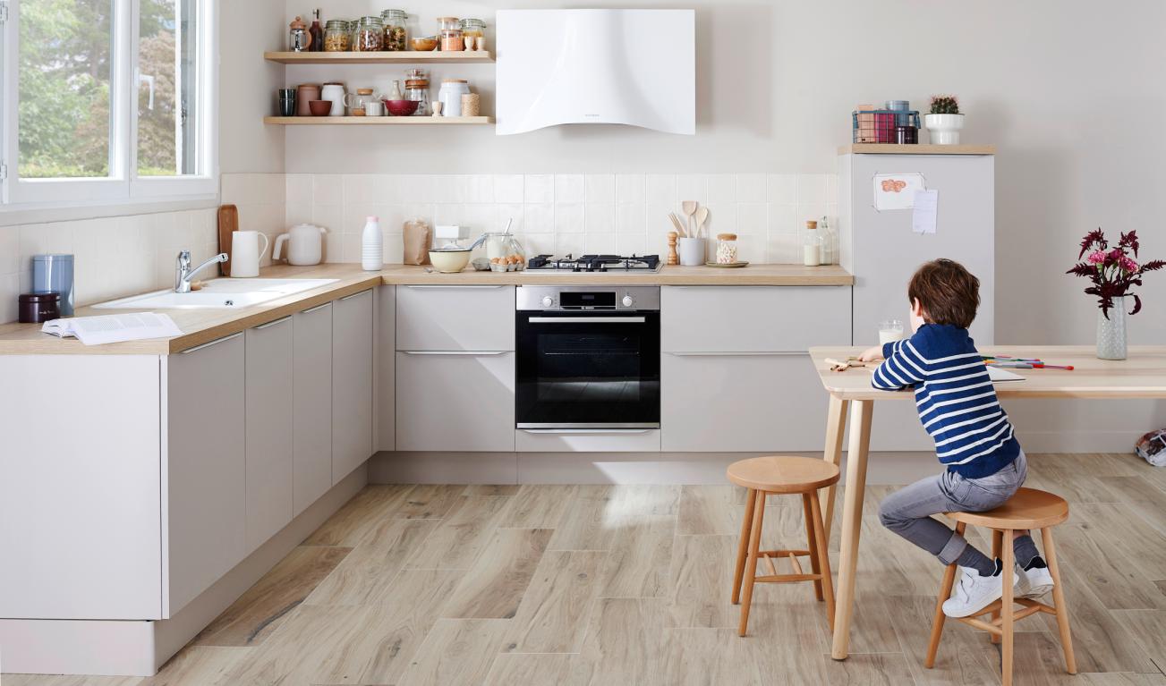 Cuisine lumineuse en L avec enfant de dos assis à table