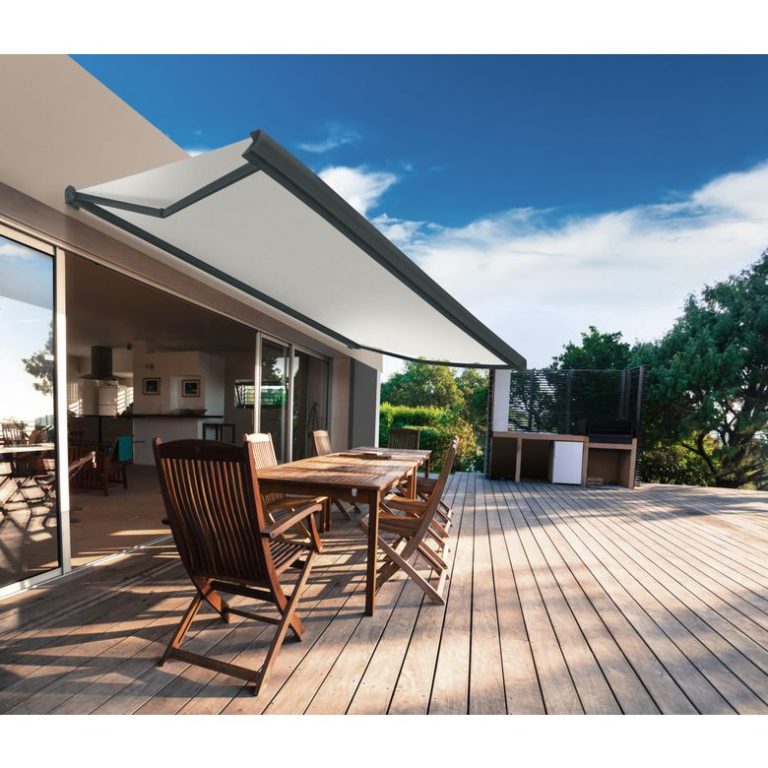 Grande terrasse en bois avec un salon de jardin. Store banne gris qui se déploie
